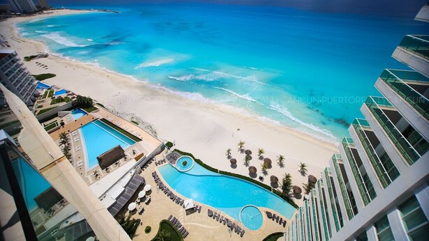 A resort with a large pool, beach, and ocean view.