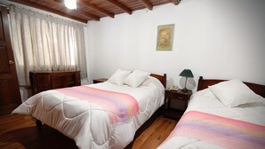 Ein Zimmer mit zwei Betten, Holzboden, einem Nachttisch mit Lampe und einem Bild an der Wand.