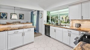Una cocina moderna con armarios blancos, encimeras de granito y lavavajillas.