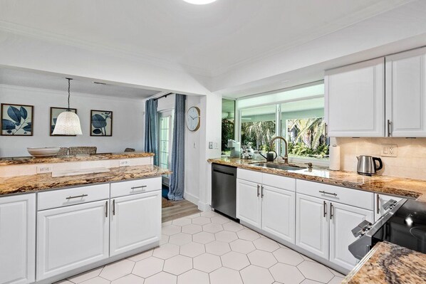A modern kitchen with white cabinets, granite countertops, and a dishwasher.