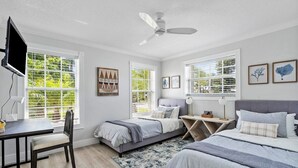 Un dormitorio con dos camas, un escritorio, una silla y un televisor.