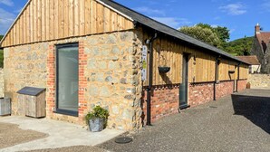 Un bâtiment rustique à l’extérieur en pierre et en bois, avec une grande porte et une petite fenêtre.