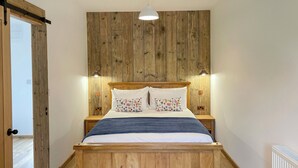 Un lit en bois avec une tête de lit, deux tables de chevet avec des lampes et un panneau mural en bois.