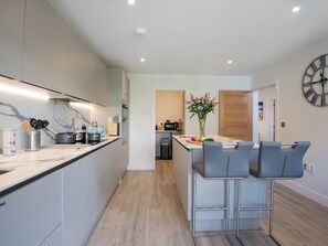 A modern kitchen with a marble countertop, stainless steel appliances, and a central island with bar stools.