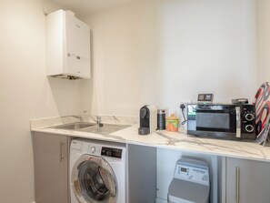 A compact laundry area with a washing machine, a dryer, a microwave, and a coffee maker.