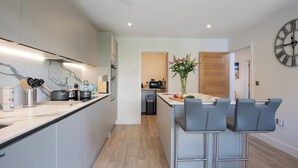 A modern kitchen with a marble countertop, stainless steel appliances, and a central island with bar stools.