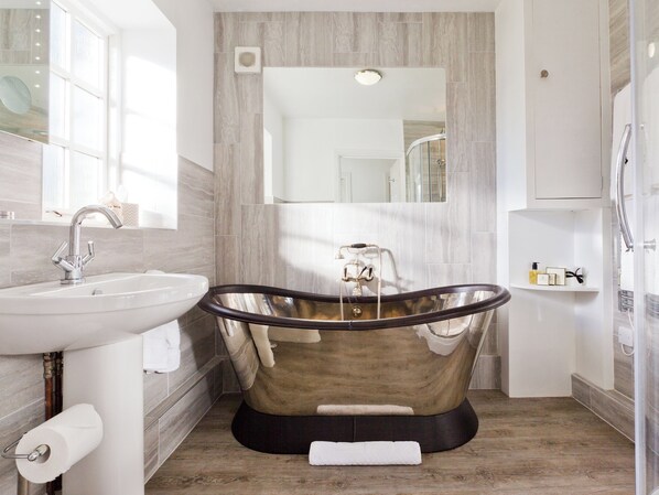A modern bathroom with a freestanding bathtub, a sink, and a mirror. - The Gatehouse Cottage (Wells)