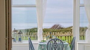 A dining area with a table set for two, overlooking a garden. - 1 bedroom accommodation in Clynnog Fawr (Clynnog Fawr)