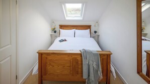 A bedroom with a wooden bed, a skylight, and a mirror. - 1 bedroom accommodation in Clynnog Fawr (Clynnog Fawr)
