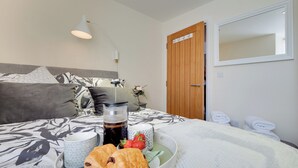 A neatly made bed with a tray of pastries, a cup of coffee, and strawberries. - 2 bedroom accommodation in Berwick-upon-Tweed (Berwick-upon-Tweed)
