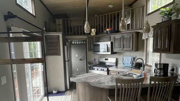Une cuisine moderne avec des meubles en bois, un îlot central et un coin repas équipé de tabourets de bar.