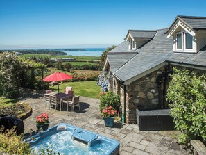 A stone house with a hot tub, patio furniture, and a view of the sea.