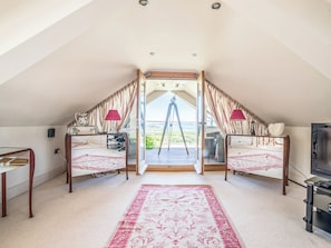Ein Schlafzimmer mit großem Fenster, einem Teleskop und einem Fernseher.
