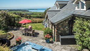 Une maison en pierre avec un jacuzzi, du mobilier de jardin et une vue sur la mer.