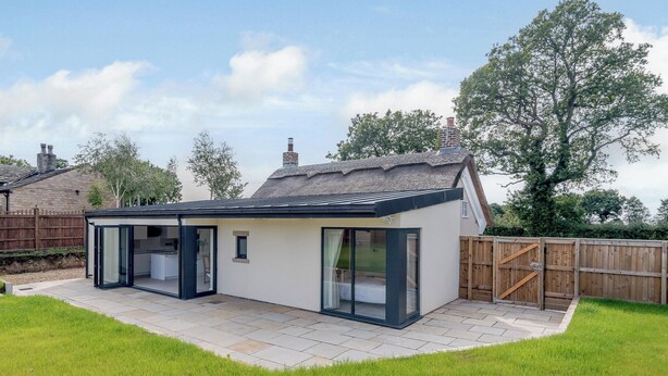 Et moderne hus med en patio, et glasindhegnet rum og et træhegn.