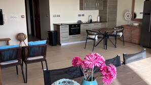 A modern living room with a dining area, kitchen, and a large window. - Appartement La Maya met Zwembad Strand Jan Thiel (Jan Thiel)