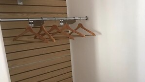 A walk-in closet with wooden paneling and a metal rod for hanging clothes. - Katie's Cozy Suites (Tombstone)