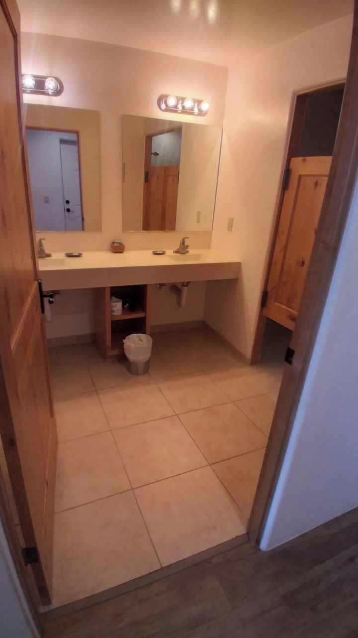 Un baño con tocador doble, espejo e iluminación en el techo.