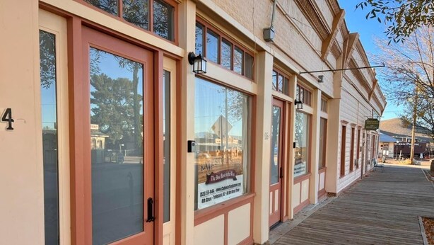 A building with large windows and a wooden deck. - Katie's Cozy Suites (Tombstone)