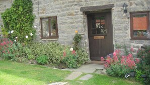 A stone building with a wooden door, a small window, and a sign reading "Badger's Barn." - Nestled in a prime location with spectacular views over open countryside. (Staintondale near Scarborough)
