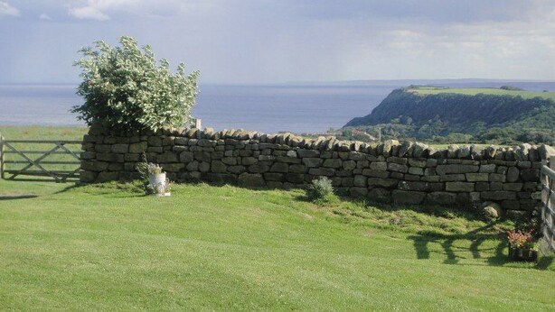 A stone wall with a tree and a view of the sea. - Nestled in a prime location with spectacular views over open countryside. (Staintondale near Scarborough)