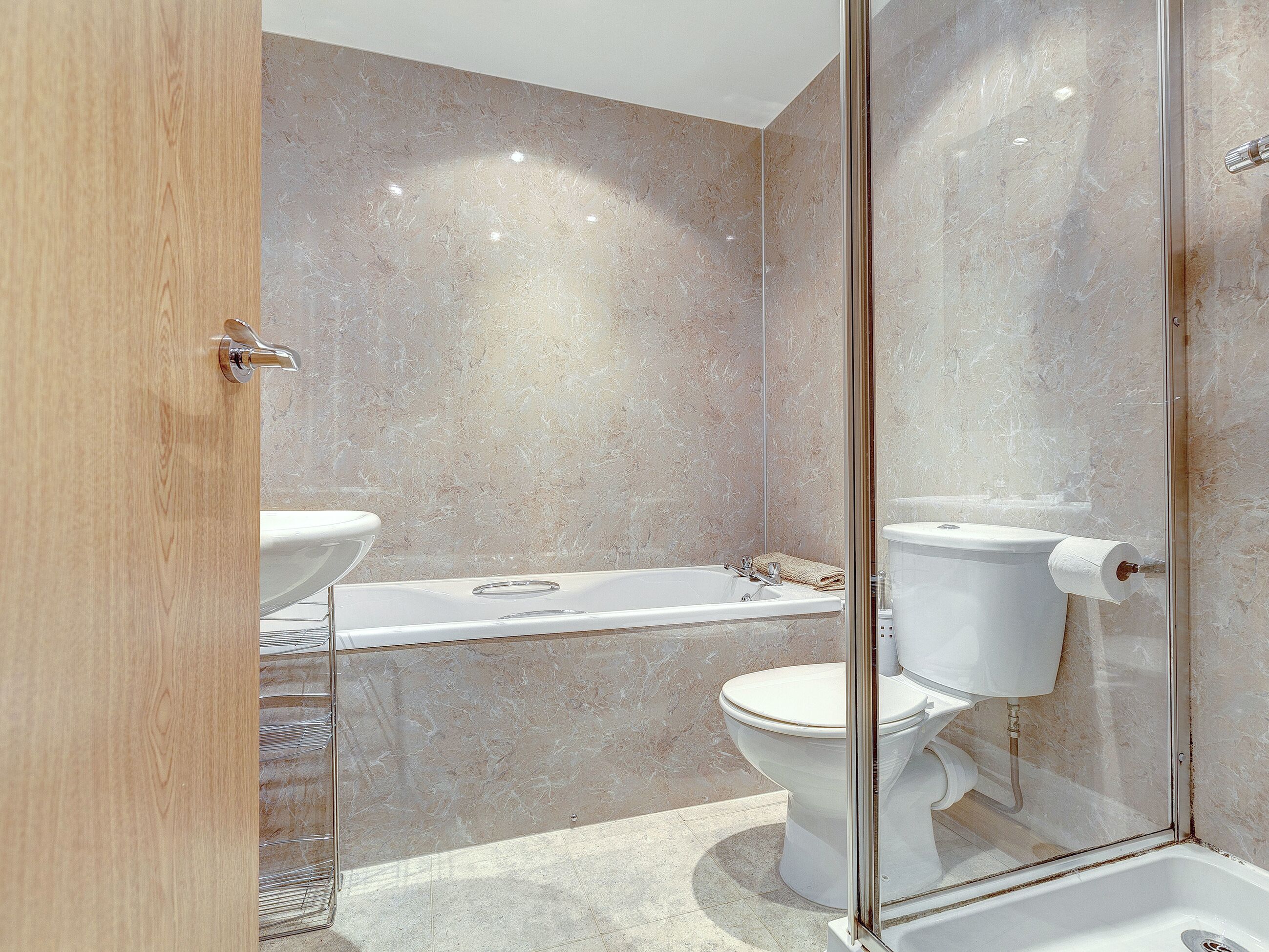 Un baño moderno con cabina de ducha de vidrio, bañera y retrete.