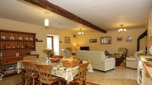 A cozy living room with a dining area, featuring a wooden table, chairs, a sofa, and a television. - 3 bedroom accommodation in Cold Eaton, Alsop-en-le-Dale (Cold Eaton, Alsop-en-le-Dale)