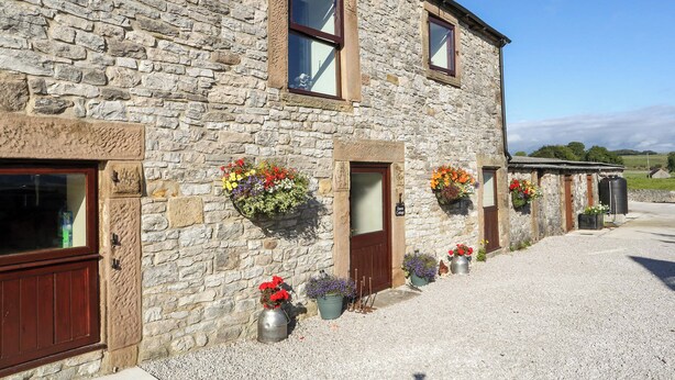 A stone building with multiple windows and doors, outdoor flower planters, and a gravel driveway. - 3 bedroom accommodation in Cold Eaton, Alsop-en-le-Dale (Cold Eaton, Alsop-en-le-Dale)