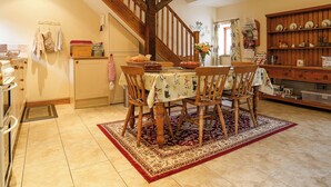 A dining area with a wooden table, chairs, and a red and beige patterned rug. A wooden staircase with exposed beams is visible in the background. - 3 bedroom accommodation in Cold Eaton, Alsop-en-le-Dale (Cold Eaton, Alsop-en-le-Dale)