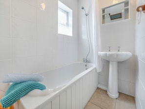 A bathroom with a bathtub, a sink, and a window.