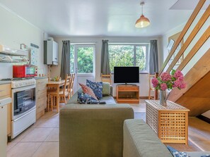 A compact living space with a kitchenette, a flat-screen TV, a sofa, and a dining area.