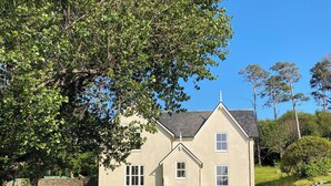A two-story house with a stone wall and a grassy yard.