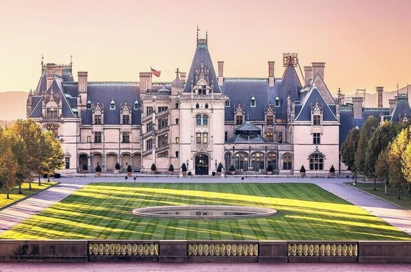 A historic building with a symmetrical facade, large windows, and a central courtyard with a circular fountain.