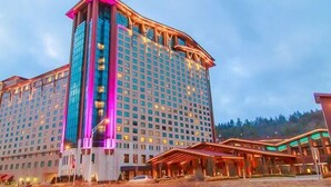 Ein großes Hotel mit modernem Design, das einen markanten Eckturm und einen gut beleuchteten Eingangsbereich aufweist.