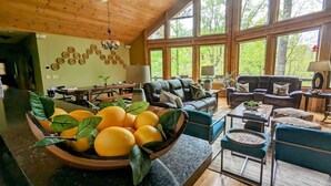 Ein geräumiger Wohnbereich mit großem Fenster, einer schwarzen Ledersofa und einer Schüssel Orangen auf einer Arbeitsfläche.
