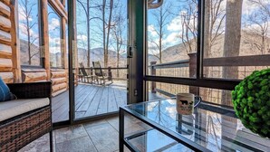 Eine Blockhütte mit Glastür, die auf eine Terrasse mit Gartenmöbeln führt.