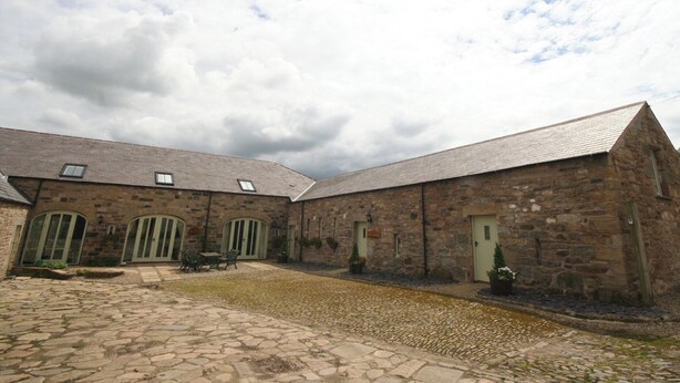 A stone building with a courtyard, featuring a cobblestone path and a table with chairs. - Lambley Farm-Orchard House (Lambley near Haltwhistle)
