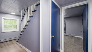 A staircase with blue steps and white railings, a blue door, and a window with a view of greenery.