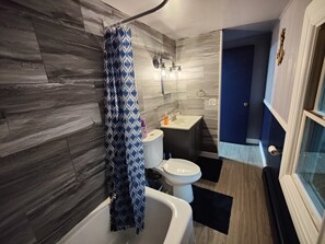 Bañera con ducha, toallas, jabón, papel higiénico