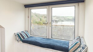 Une pièce dotée d’une banquette intégrée, située près d’une grande fenêtre donnant sur une rivière et la verdure.