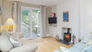 Un salon confortable avec un canapé, un téléviseur, une cheminée et une porte-fenêtre coulissante donnant sur un balcon.