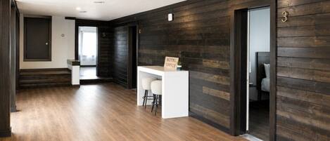 A hotel lobby with a reception desk, a staircase, and a dark wooden wall.