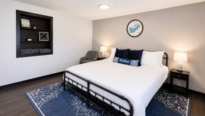 Une chambre d’hôtel comprenant un lit, deux tables de chevet, une chaise, une étagère murale et un tapis.