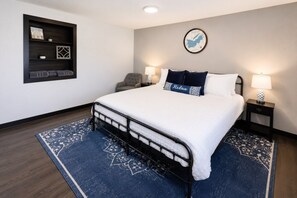 A hotel room with a bed, two bedside tables, a chair, a wall shelf, and a rug.