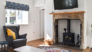 Una sala de estar con sofá, televisión, chimenea y ventana con vista al exterior.