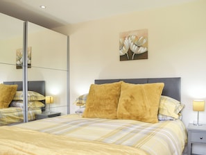 A bedroom with a bed, two bedside tables, a mirror, and artwork on the wall.