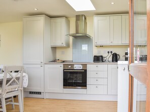 A kitchen with white cabinets, a stainless steel oven, and a window above the stove.