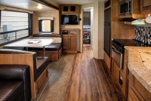 Una cocina compacta para vehículos recreativos con comedor, televisor y microondas.