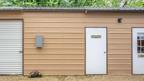 A building with a closed white garage door, a beige exterior, and a sign indicating a game cleaning room.