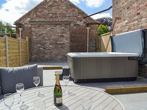 A patio area with a round table, a bottle of champagne, and a hot tub.